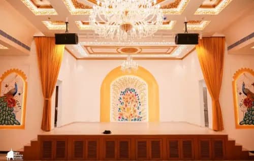 The stage in Dwaraka Palace, with orange curtains and a chandelier